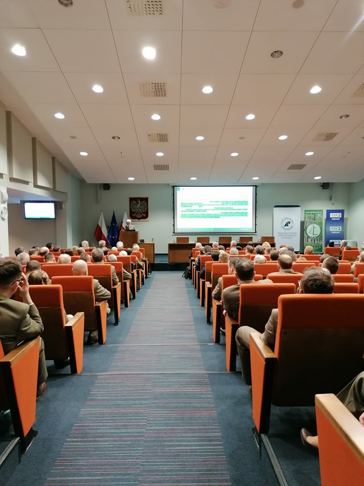 Zdjęcie przedstawia widok od tyłu wypełnionej gośćmi sali konferencyjnej z odbywającą się na podium prezentacją. Fot. T. Maćkowiak (RDLP w Poznaniu). 